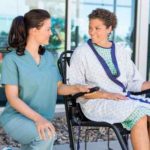 Patient Looking At Nurse While Sitting On Wheelchair